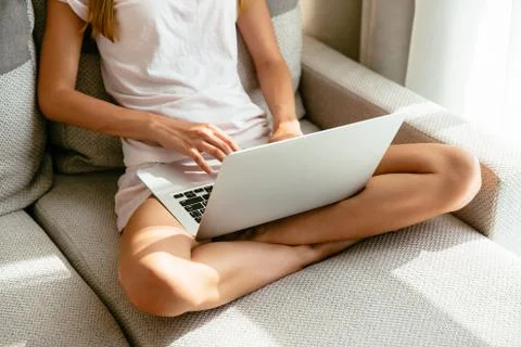 Woman using laptop while sitting on sofa at home Stock Photos