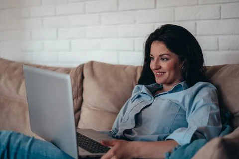 Woman using laptop while sitting on the couch at home Stock Photos