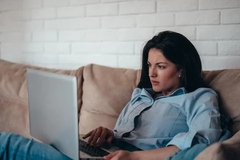 Woman using laptop while sitting on the couch at home Stock Photos