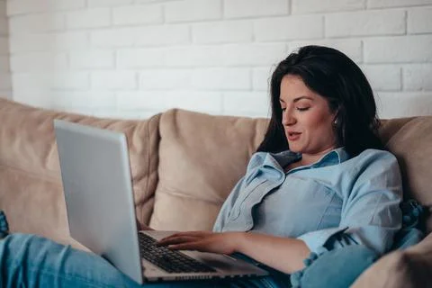 Woman using laptop while sitting on the couch at home Stock Photos