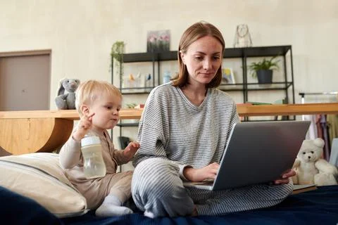 Woman using laptop while sitting with baby Stock Photos