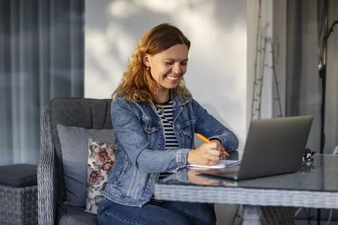 Woman using laptop while sitting at table on terrace Foto stock