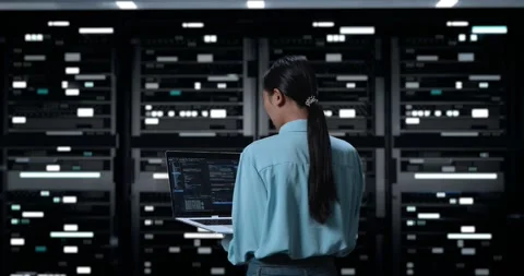 Woman Using A Laptop Writing Code In Server Room Database. Showing Database Stock Footage 248005364