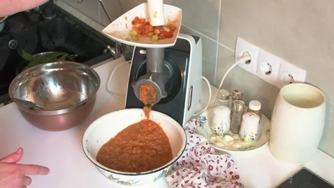 A woman is using a meat grinder to grind stewed vegetables into a bowl for .. Video stock 346148832