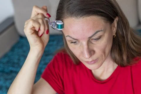 Woman using micro needle skin care derma roller on her face and neck. Cosmeti Stock Photos