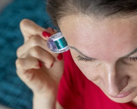 Woman using micro needle skin care derma roller on her face and neck. Cosmeti Stock Photos