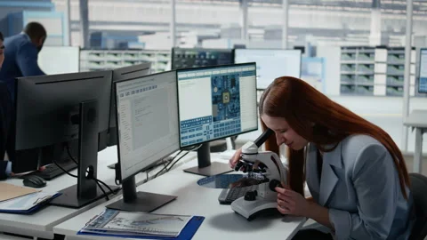 Woman using microscope in office, reviewing semiconductor substrates Stock Footage 335879316