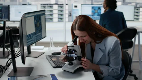 Woman using microscope in office, reviewing semiconductor substrates Stock Footage 335881190