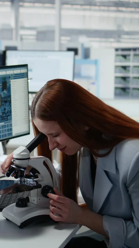 Woman using microscope in office, reviewing semiconductor substrates Stock Footage 335883052