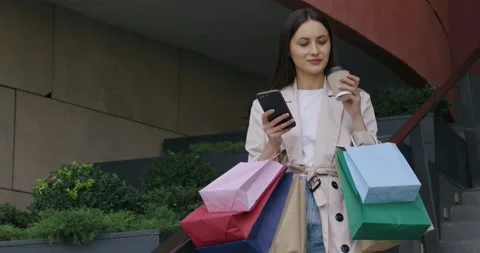 Woman using mobile and drinking coffee near shopping mall Stock Footage 162075647