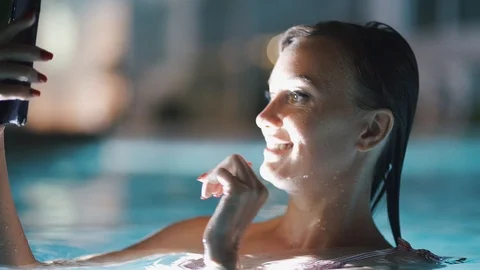 Woman using mobile cell phone app on vacation in pool at night on travel Stock Footage 113612109