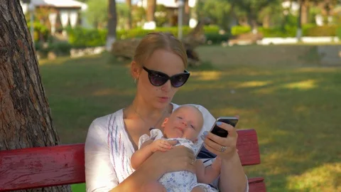 Woman using mobile during outing with baby in the park Stock-Footage 86200478