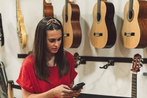 Woman using the mobile in a instruments store Stock Photos