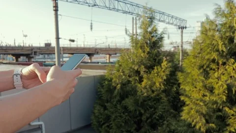 Woman using a mobile phone on the background of the bridge Stockbeeldmateriaal 77870787