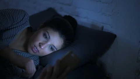 Woman using mobile phone in bed at night Stock Footage 87319665