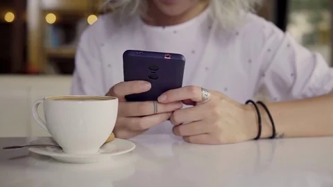 Woman using mobile phone while drinking coffee Stock Footage 83609952
