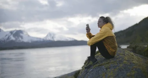 Woman using mobile phone while sitting on mossy rock Stock Footage 85964651