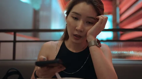 A woman using a mobile phone while waiting for food Stock Footage 276088723