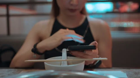 A woman using a mobile phone while waiting for food Stock Footage 276088760