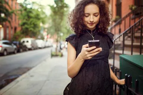Woman using mobile phone while standing against building Fotos de archivo