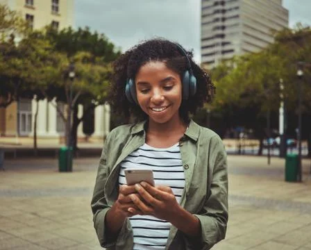 Woman using mobile phone while listening music on headphone Stock Photos