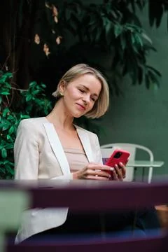 Woman using a mobile phone while sitting outdoors. Stock Photos