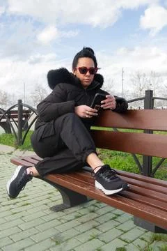 Woman using mobile phone while relaxing on bench in park Stock Photos