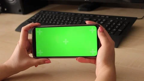 Woman using mobile smart phone with green screen on table with computer and Видео 178515849