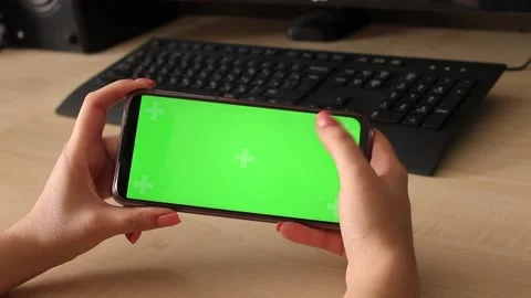 Woman using mobile smart phone with green screen on table with computer and Видео 187390911