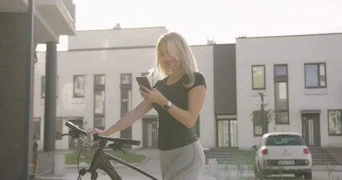 Woman using mobile while standing with bike on street Stock Footage 160927934