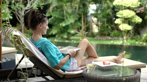 Woman using modern notebook while sitting next to the swimming pool, steadycam s Stock-Footage 79221706