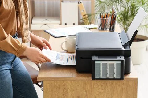 Woman using modern printer on desk in office Stock Photos