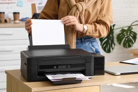 Woman using modern printer on desk in office Stock Photos