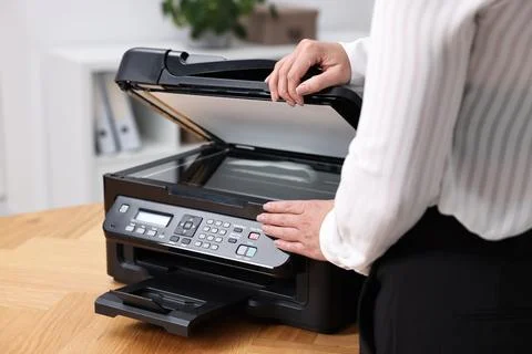 Woman using modern printer at workplace indoors, closeup Foto stock