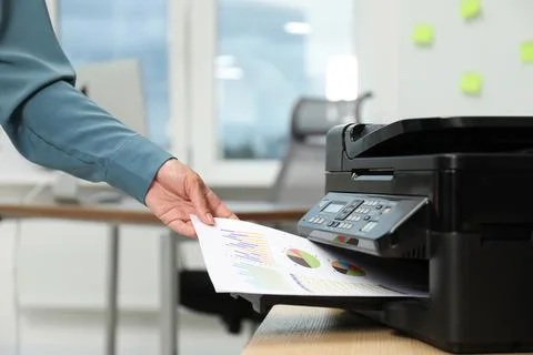 Woman using modern printer at workplace indoors, closeup Stock Photos