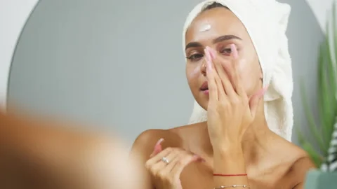 Woman using moisturizing face cream and smiling, morning skincare routine. Young Stock Footage 160921098