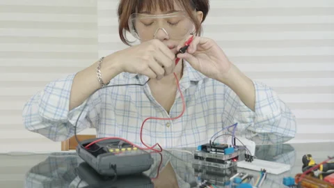 Woman is using a multimeter to check the microcontroller's functionality. Stock Footage 334764554