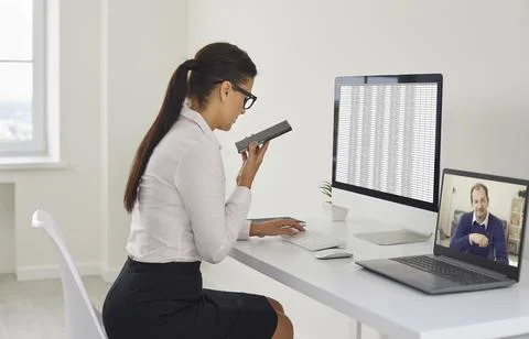 Woman using multiple devices and computers while working at her desk in the Foto stock