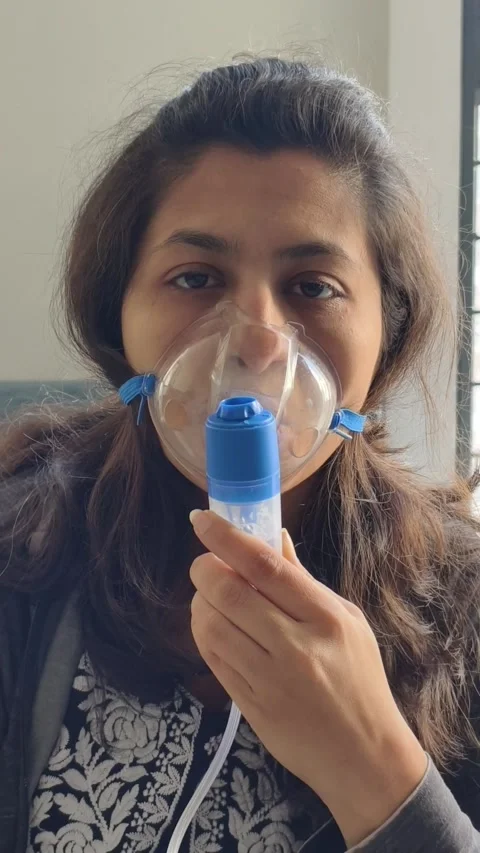Woman using a nebulizer for breathing therapy, receiving respiratory treatment. Stock Footage 323699332