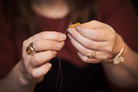 A woman using a needle threaded with cotton thread. Stock Photos