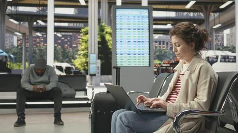 Woman using notebook in bus terminal to check travel details Stock Photos