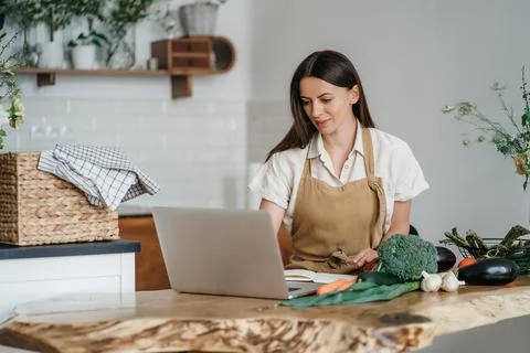 Woman using notebook during cooking vegetables Foto stock