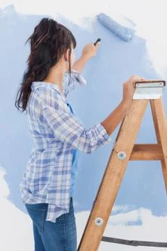 Woman using paint roller to paint wall blue Stock Photos