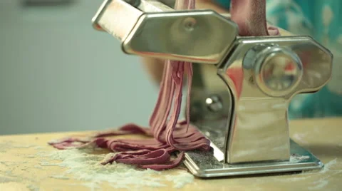 Woman using a pasta maker to make pasta with purple beet color Video stock 64050651