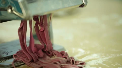 Woman using a pasta maker to make pasta with purple beet color Stock Footage 64050661