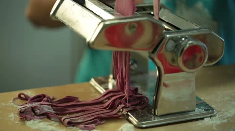 Woman using a pasta maker to make pasta with purple beet color Stock Footage 64050683