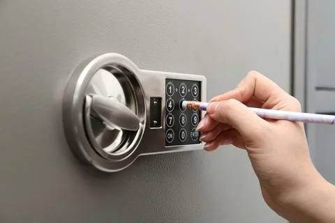 Woman using pencil to enter code on keypad of modern safe, closeup Stock Photos