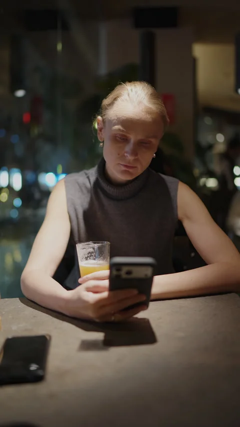 Woman Using Phone and Drinking Beer in a Bar at Night Stock-Footage 335449758