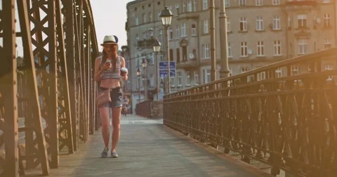 Woman using phone, drinking coffee, walking in the European city. Slow Motion. Stockbeeldmateriaal 53558007