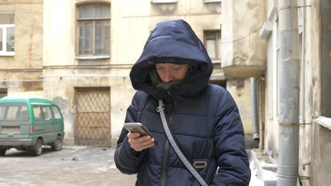 Woman using a phone mobile device on a winter. old yard of a European type Stock Footage 86254620